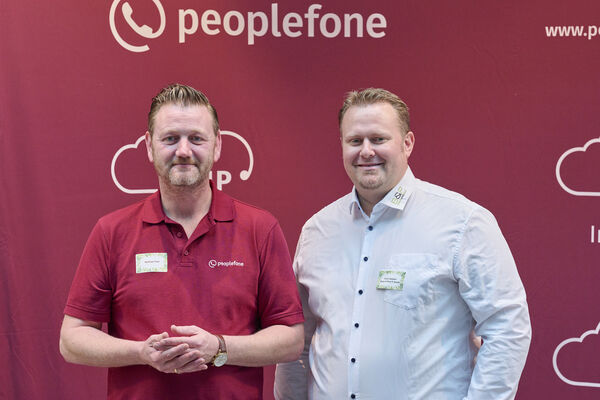 Partner der peoplefone stehen vor einer Fotowand