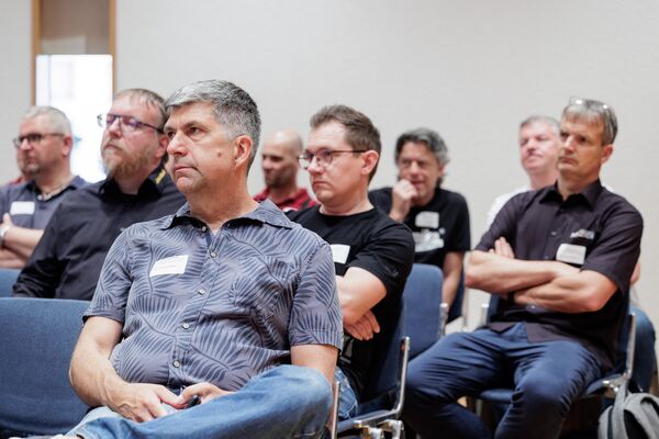 Personen sitzend hören einem Vortrag zu.