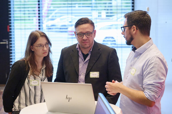 Personen stehen am Messestand und unterhalten sich.