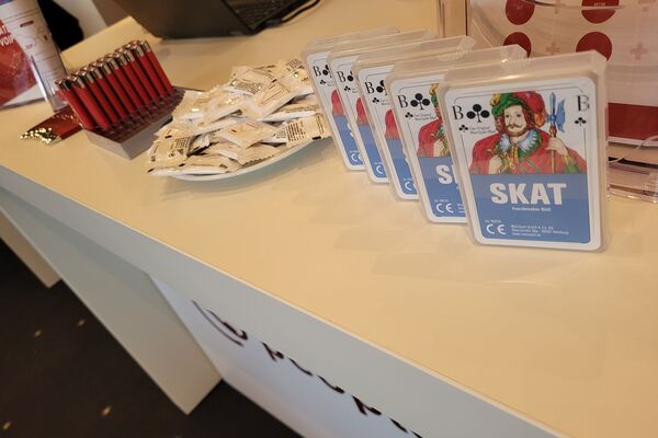 Messetheke mit Kartenspiel, Feuerzeuge und Prospekte.