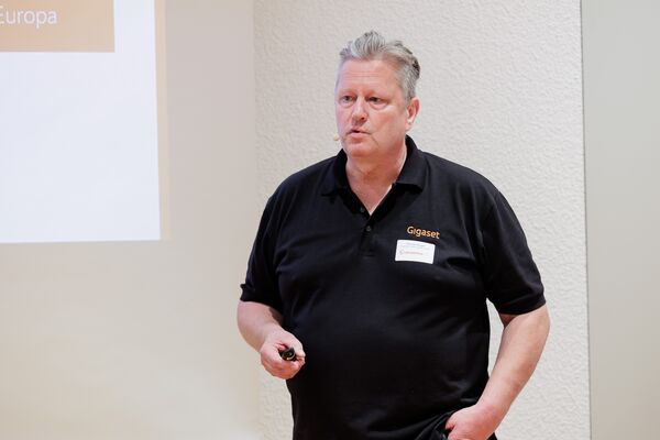 Eine Person steht vor einer Leinwand und hält einen Vortrag.