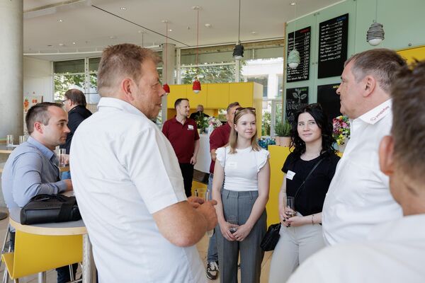 Mehrere Personen stehen an Tischen und unterhalten sich.
