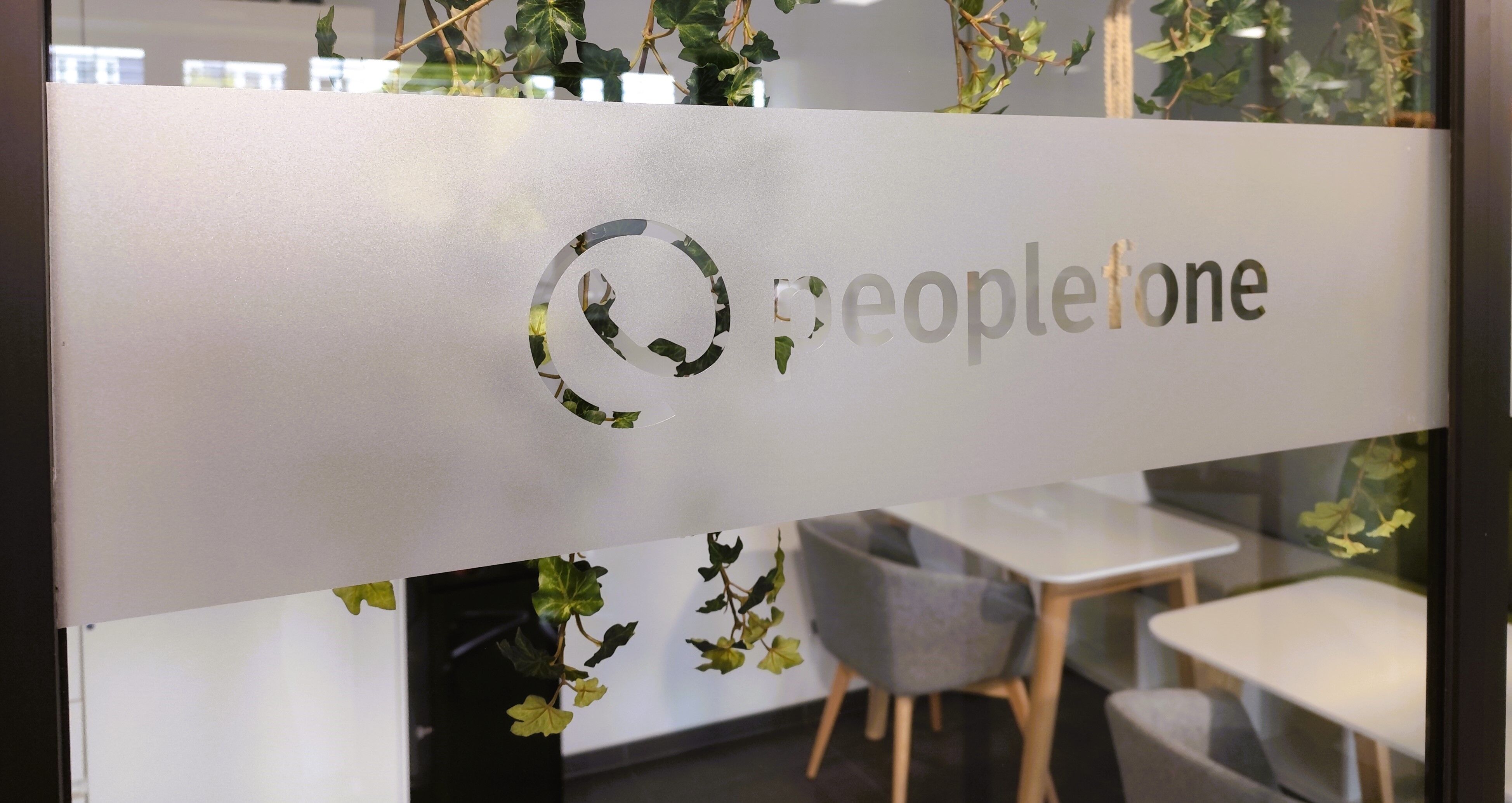 Glaswand mit peoplefone Logo und Blick in einen Raum.