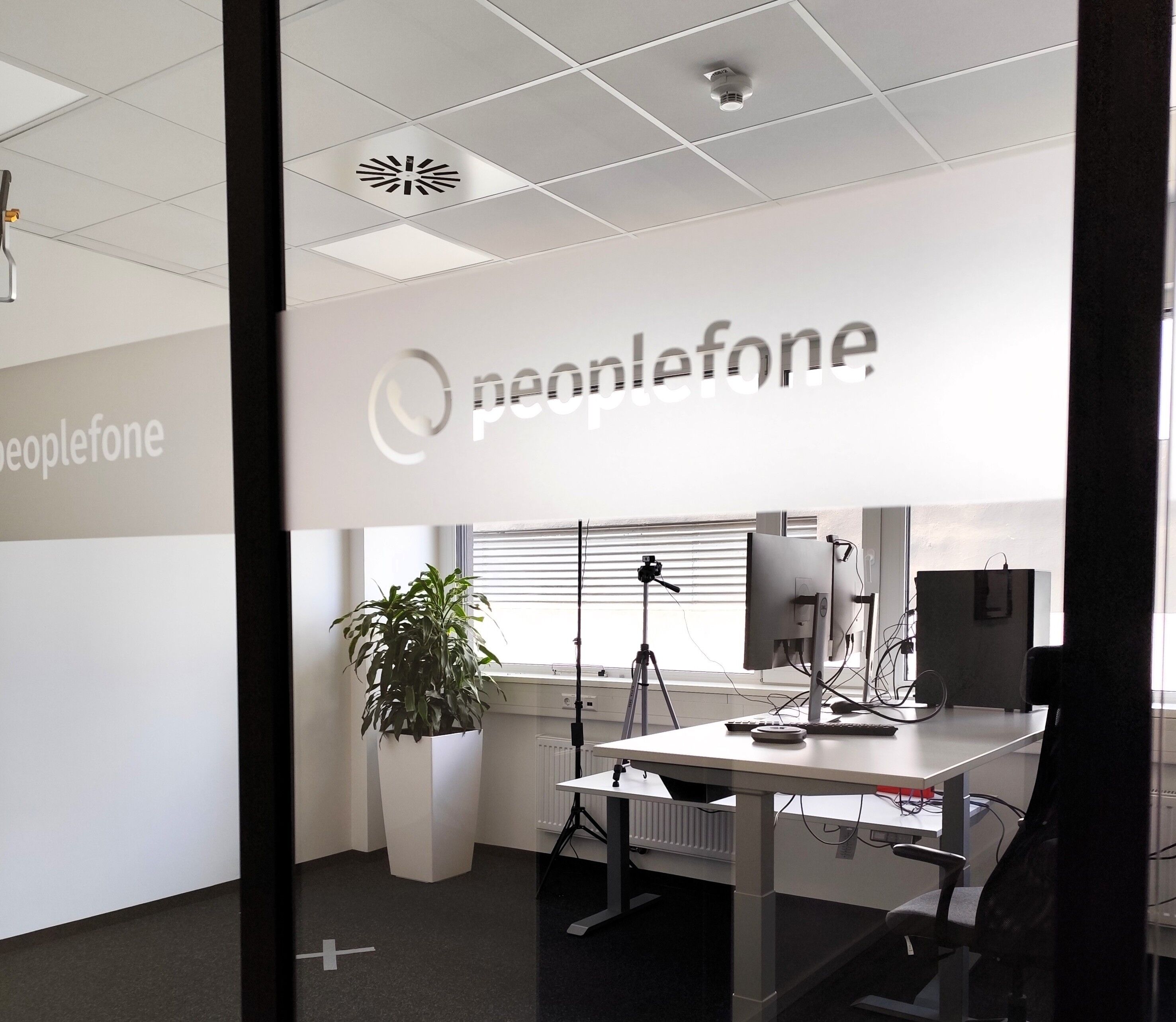 Blick durch eine Glasscheibe in einen Studioraum.