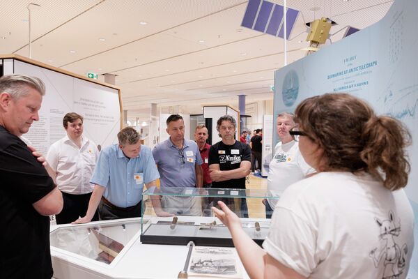 Mehrere Personen stehen in der Ausstellung und hören zu.