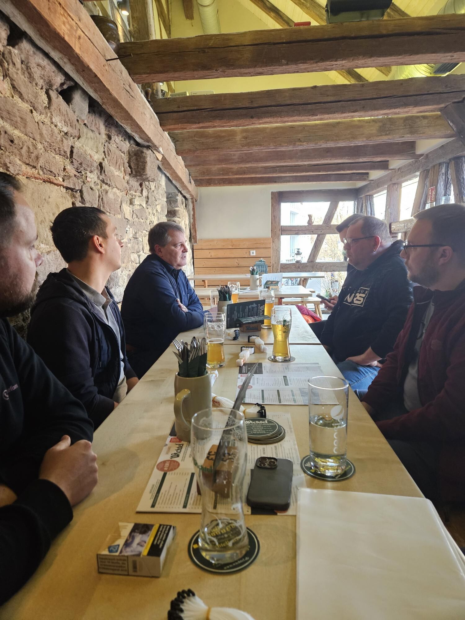 Personen sitzen an einem langen Tisch und unterhalten sich.