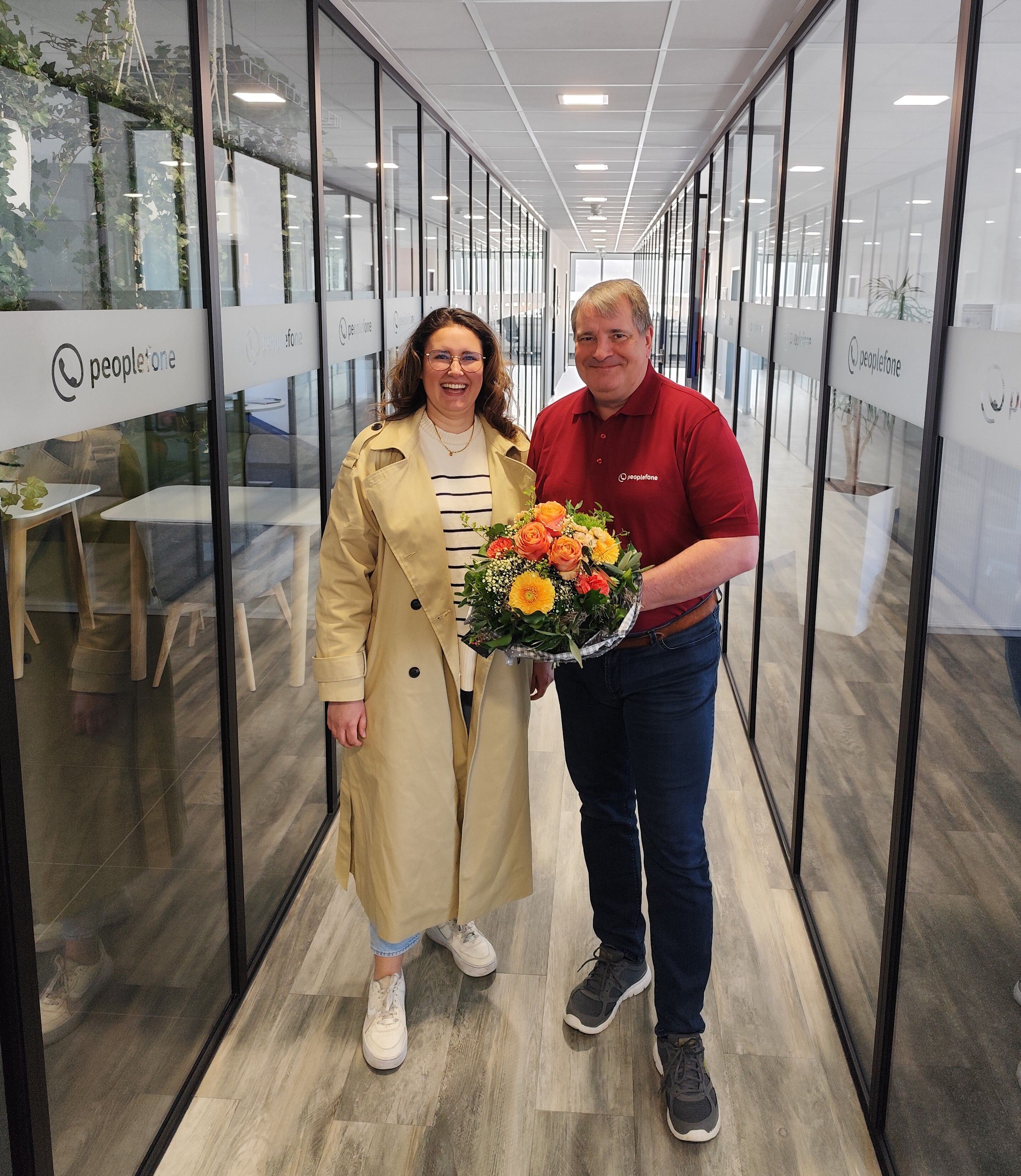 Zwei Personen stehen im Flur und übergeben einen Blumenstrauß