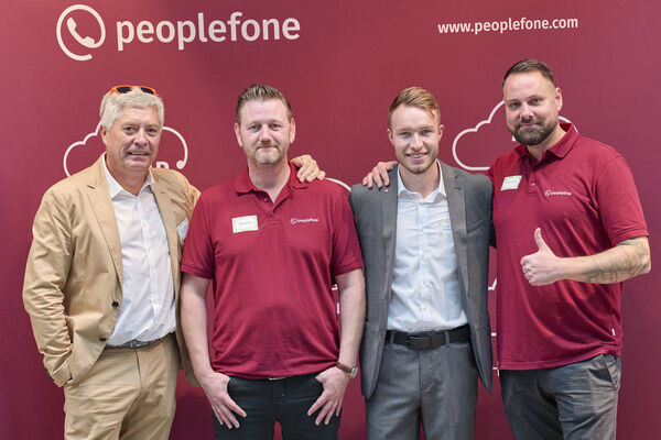 Partner der peoplefone stehen vor einer Fotowand