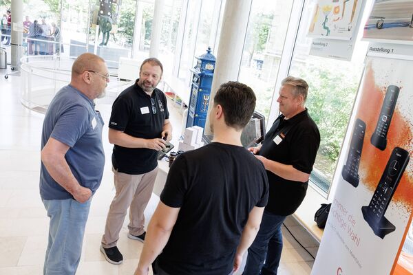 Mehrere Personen stehen an einem Messestand und unterhalten sich.