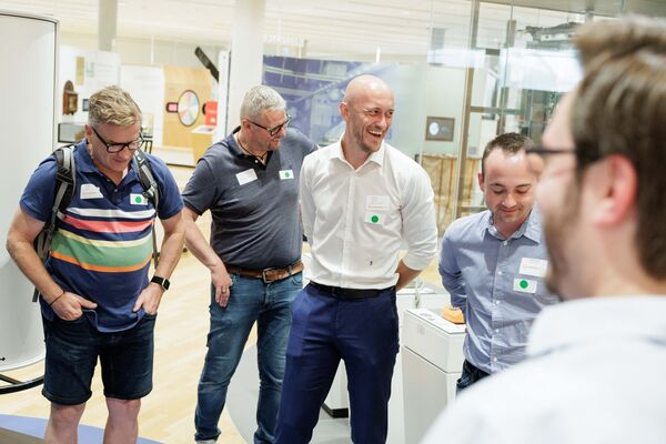 Mehrere Personen stehen in der Ausstellung und hören zu.