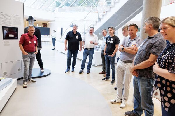 Mehrere Personen stehen in der Ausstellung und hören zu.