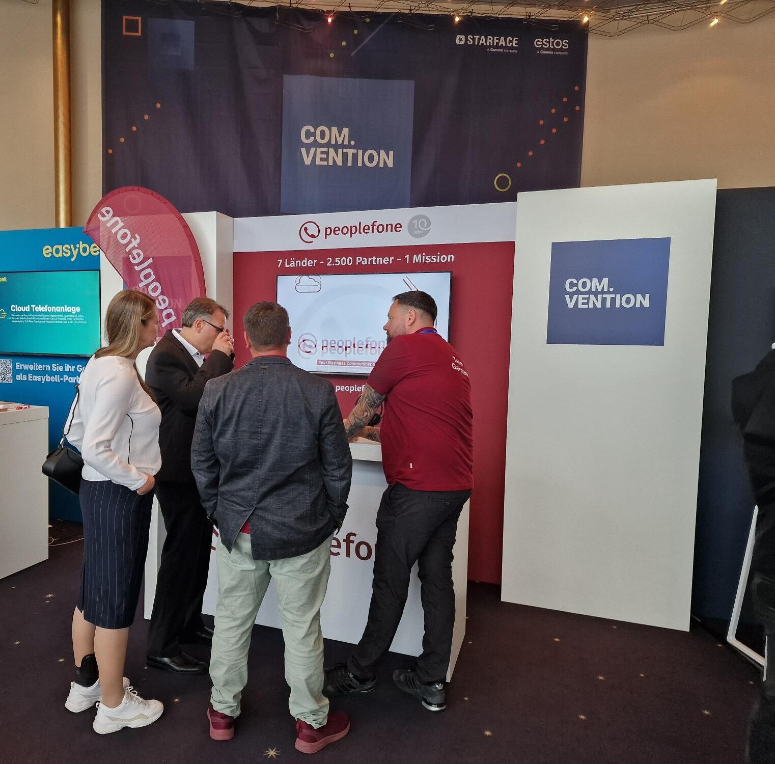 Mehrere Personen stehen vor einem Messestand und diskutieren.