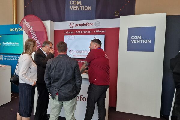 Mehrere Personen stehen vor einem Messestand und diskutieren.