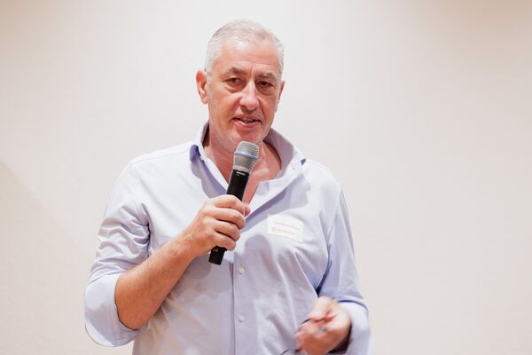 Eine Person steht vor einer Leinwand und spricht in ein Mikrofon.