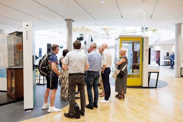 Mehrere Personen stehen in der Ausstellung und hören zu.