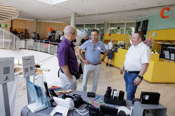 Bildausschnitt von Besuchern an einem Messestand im Gespräch.