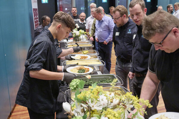 Personen stehen am Hauptspeisenbuffet und werden bedient.