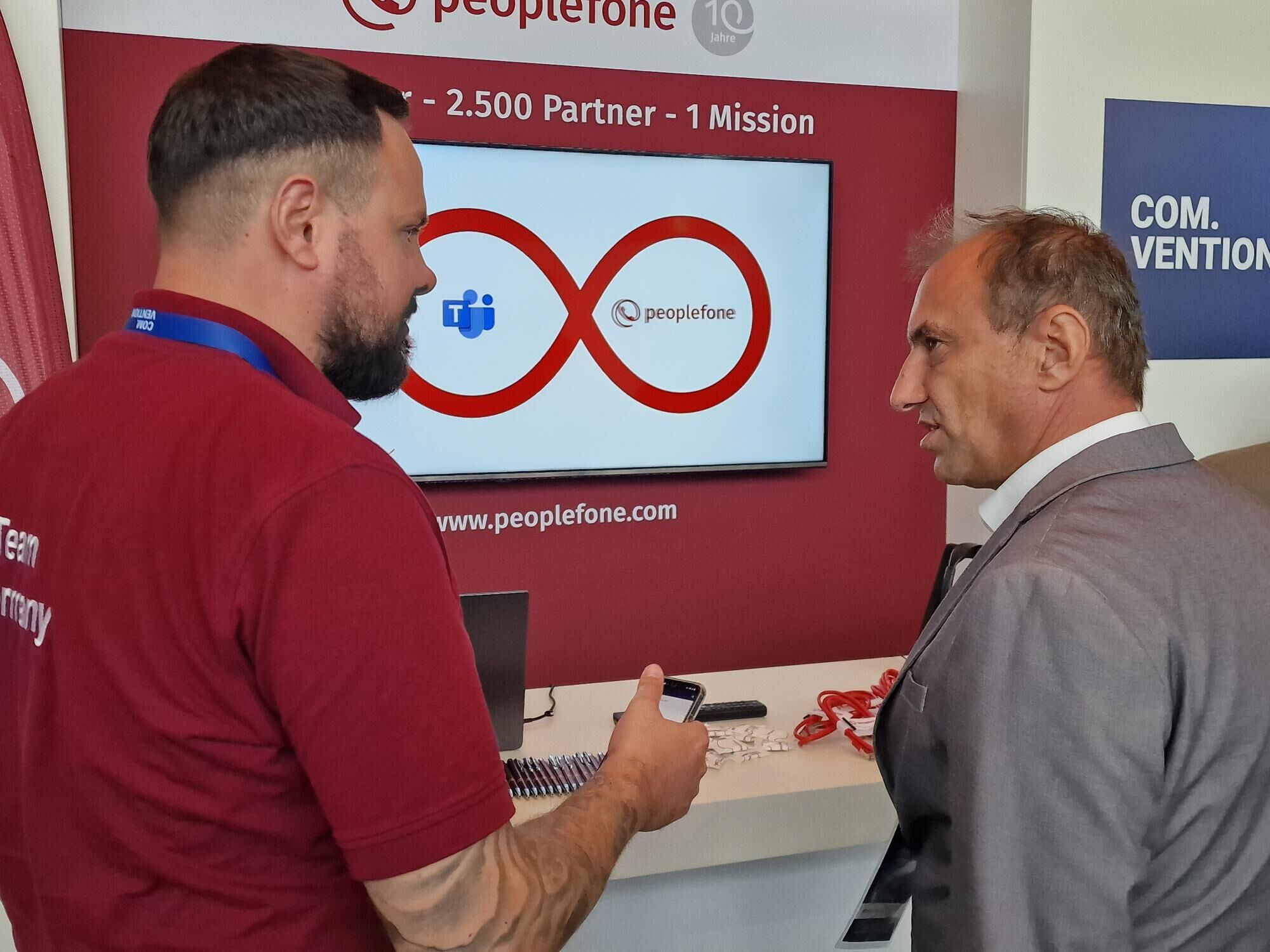 Zwei Personen vor einem Messestand unterhalten sich.