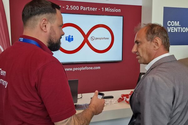 Zwei Personen vor einem Messestand unterhalten sich.