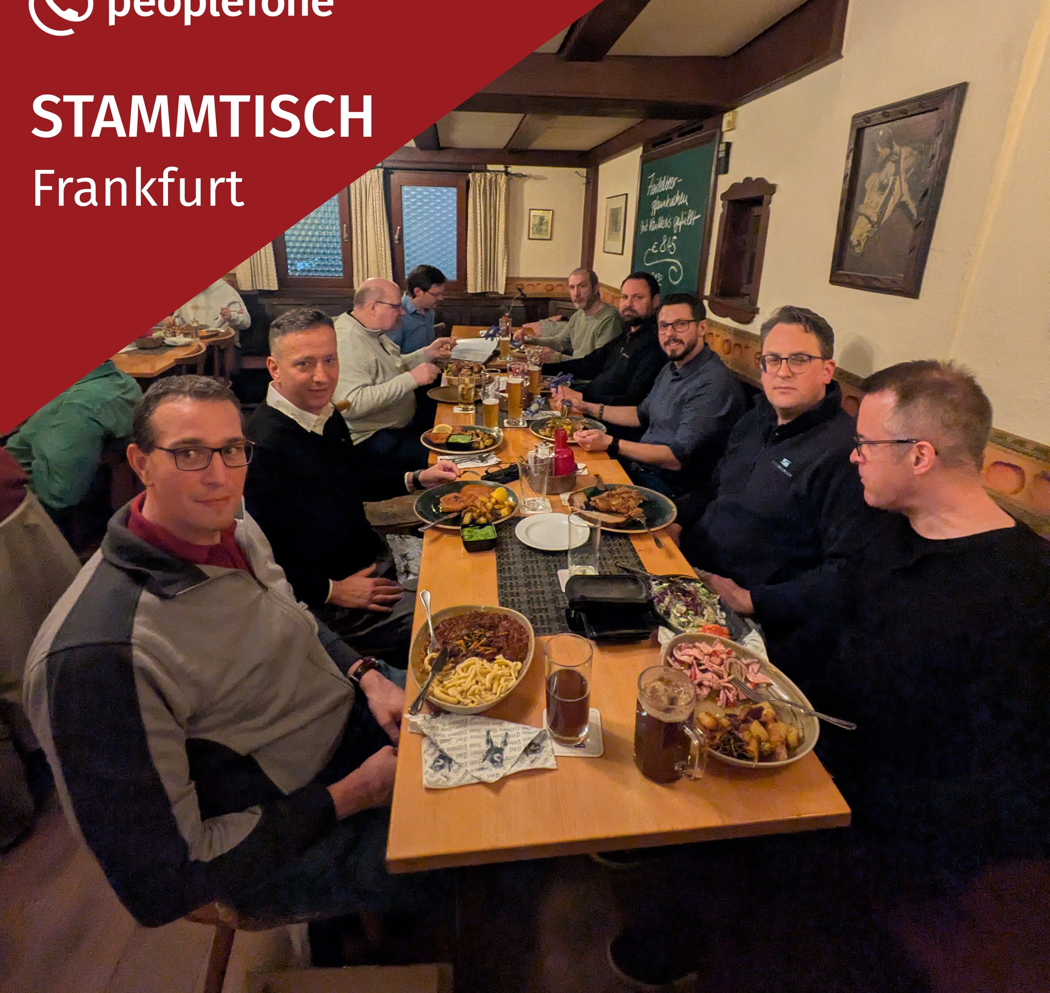 Mehrere Personen sitzen an einem langen Tisch und essen.
