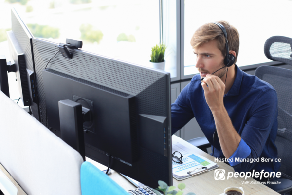 Mann am Schreibtisch sitzend telefoniert mit einem Headset.