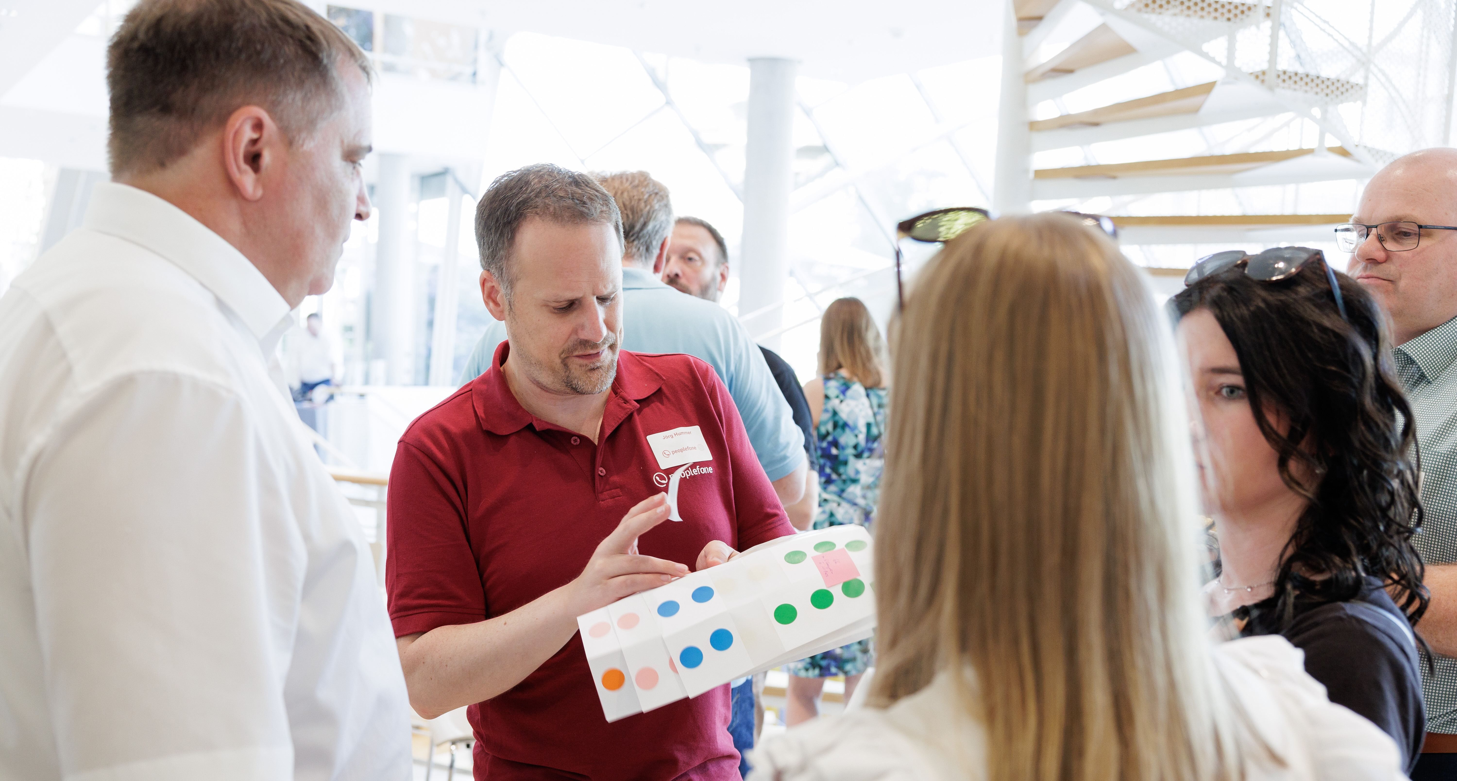 Eine Person steht in einer Gruppe und verteilt bunte Aufkleber.