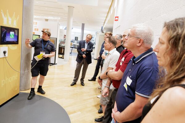 Mehrere Personen stehen in der Ausstellung und hören zu.