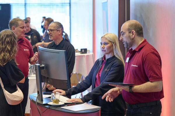 Personen stehen am Messestand und unterhalten sich.