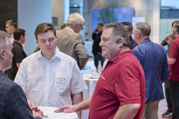 Personen stehen am Messestand und unterhalten sich.