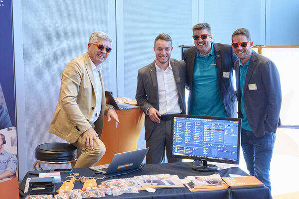 Personen stehen am Messestand und unterhalten sich.