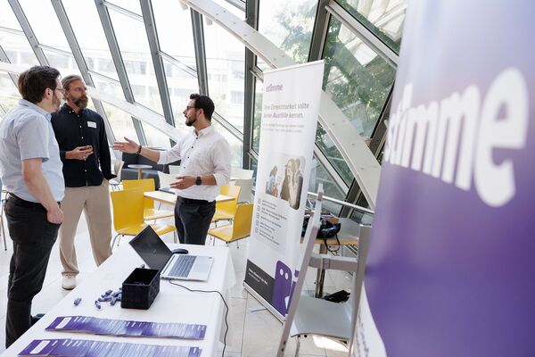 Bildausschnitt von Besuchern an einem Messestand im Gespräch.