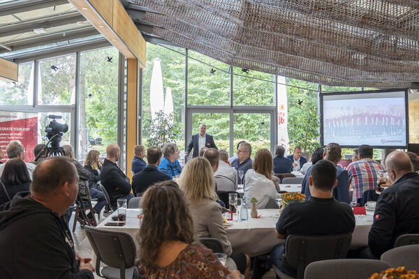 peoplefone Partner sitzend an Tischen hören einem Vortrag zu.