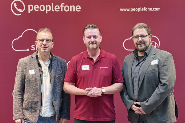 Partner der peoplefone stehen vor einer Fotowand