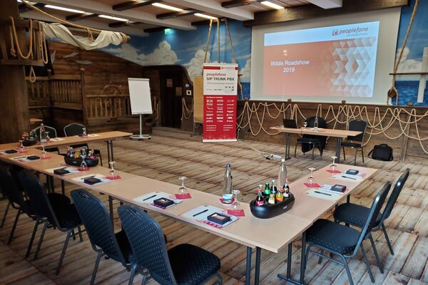 Tische und Stühle in einer U-Form aufgestellt, mit Blick auf eine Leinwand.