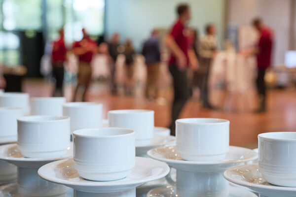 Kaffeetassen auf einer Theke. Im Hintergrund sind Gäste im Foyer sichtbar.