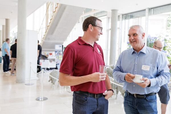 Zwei Personen stehen im Foyer und unterhalten sich.