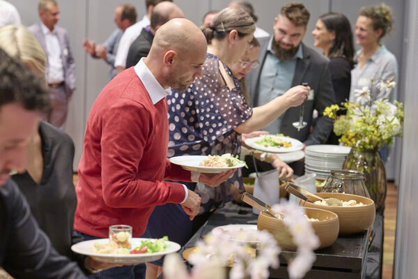 Personen stehen am Vorspeisenbuffet und bedienen sich.