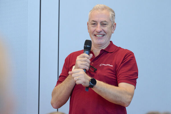 Christophe Beaud steht vor der Bühne und hat ein Mikrofon in der Hand.